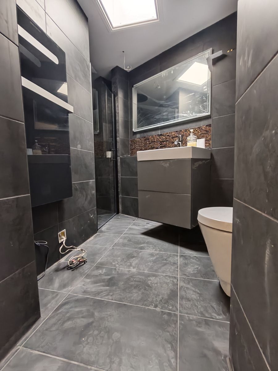 Bathroom with large dark grey floor and wall tiles, wall-hung vanity unit and wall-hung toilet